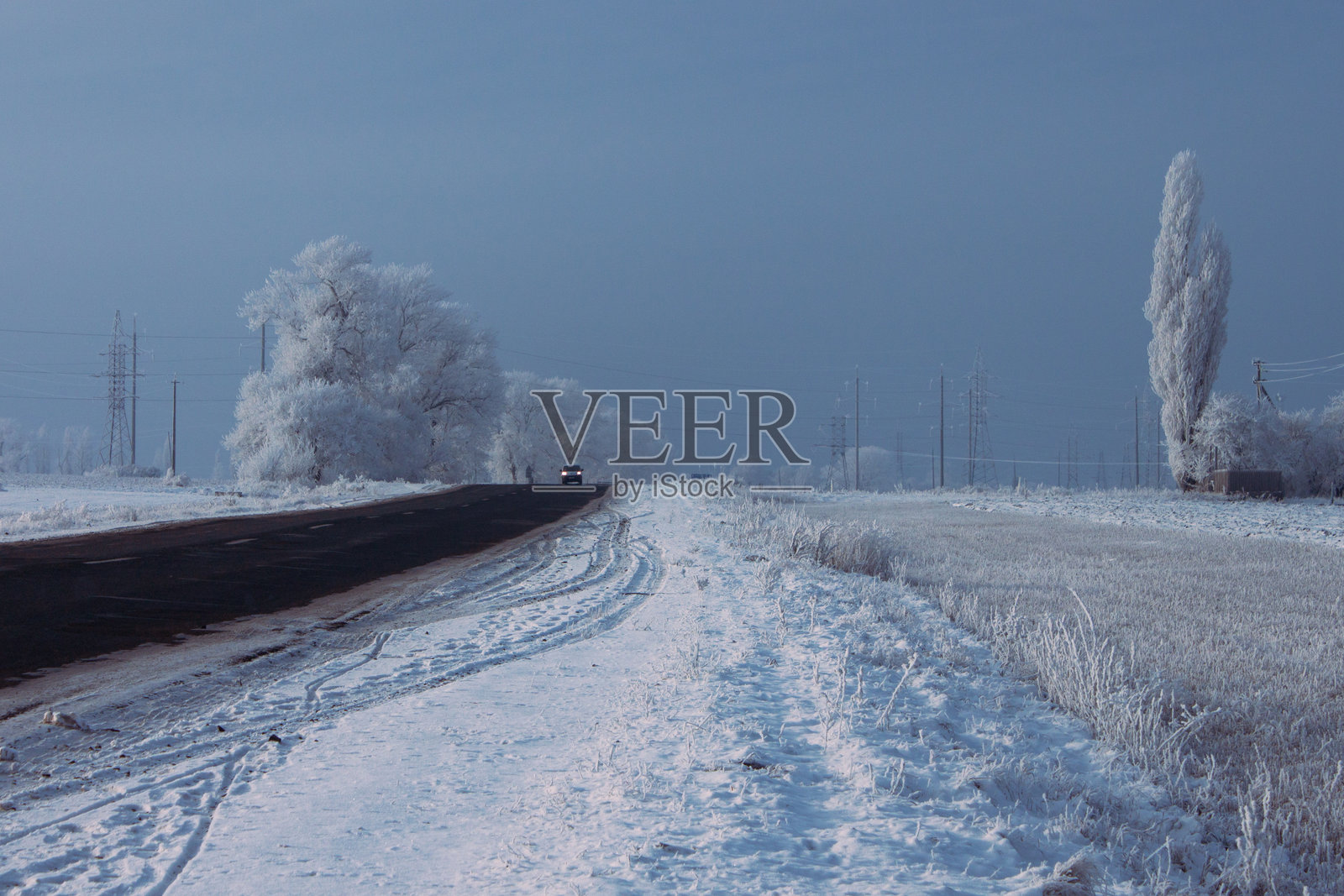 白雪覆盖的画面，蓝天与黑色道路相映成趣照片摄影图片