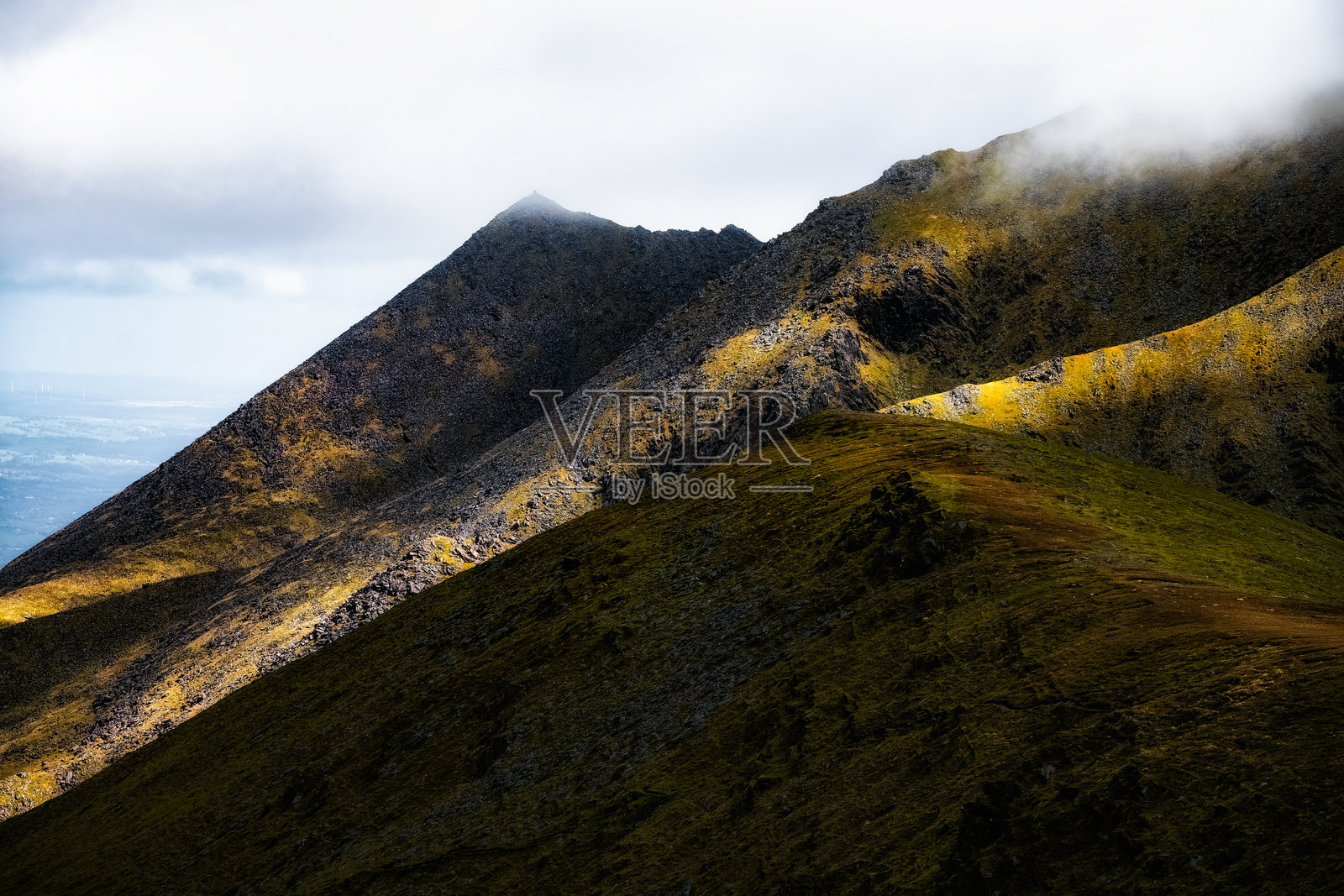 卡朗图希尔步道，爱尔兰最高峰，周围是戏剧性的风景和起伏的山丘，笼罩在阴郁的天空下。照片摄影图片