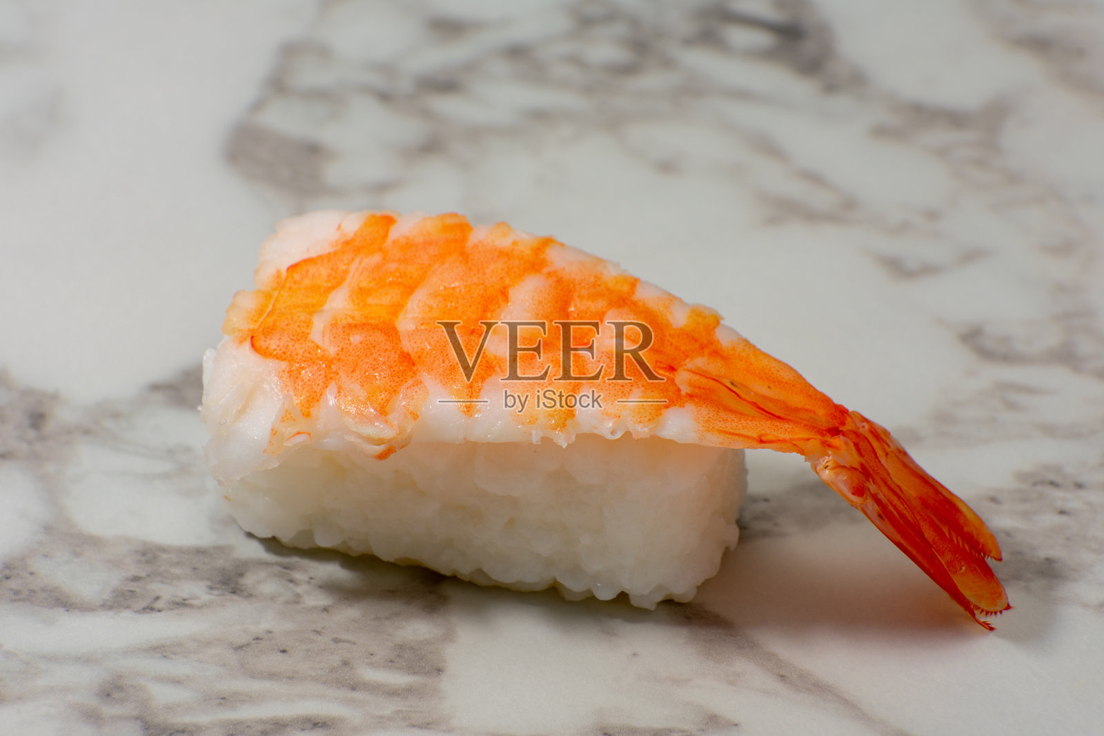 新鲜的虾握寿司，上面放着饱满的虾，搭配完美形状的白米，展示在白色表面上。这是日本烹饪艺术的经典表现。照片摄影图片