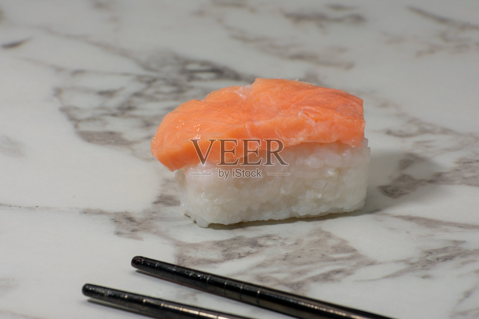 精致的鲑鱼握寿司，鲜嫩的三文鱼放在白米饭上，摆放在白色表面上。这是对日本料理简单而优雅的呈现。照片摄影图片