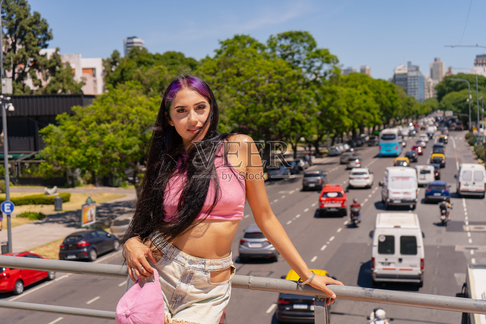 微笑的年轻拉丁裔女性，黑色长发，靠在栏杆上。照片摄影图片