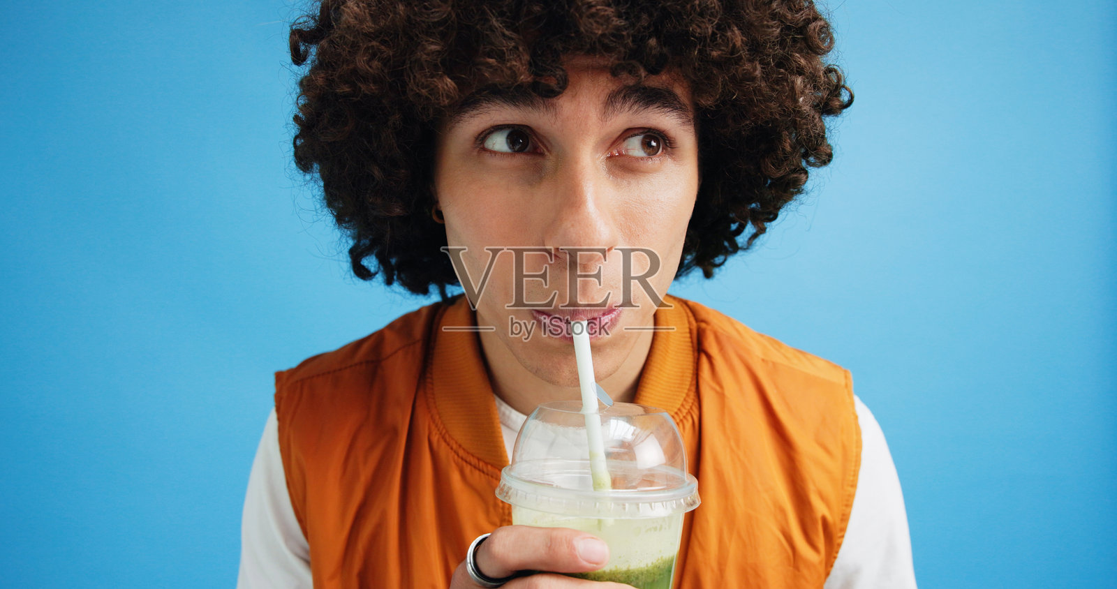 工作室，男性营养师与健康饮品，消化健康的果昔，思考中的果汁。男性营养师与绿色奶昔的排毒，饮食与营养，蓝色背景。照片摄影图片