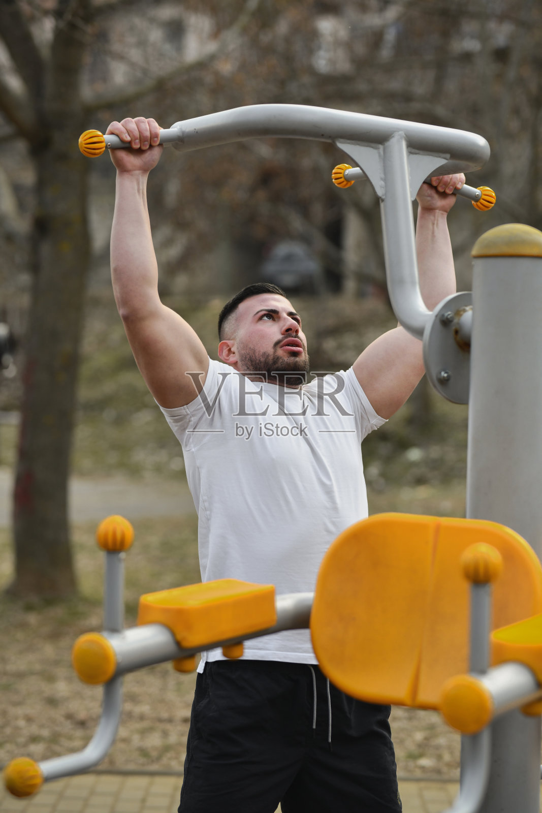 男性运动员在健身器械上悬挂时拉伸背部照片摄影图片