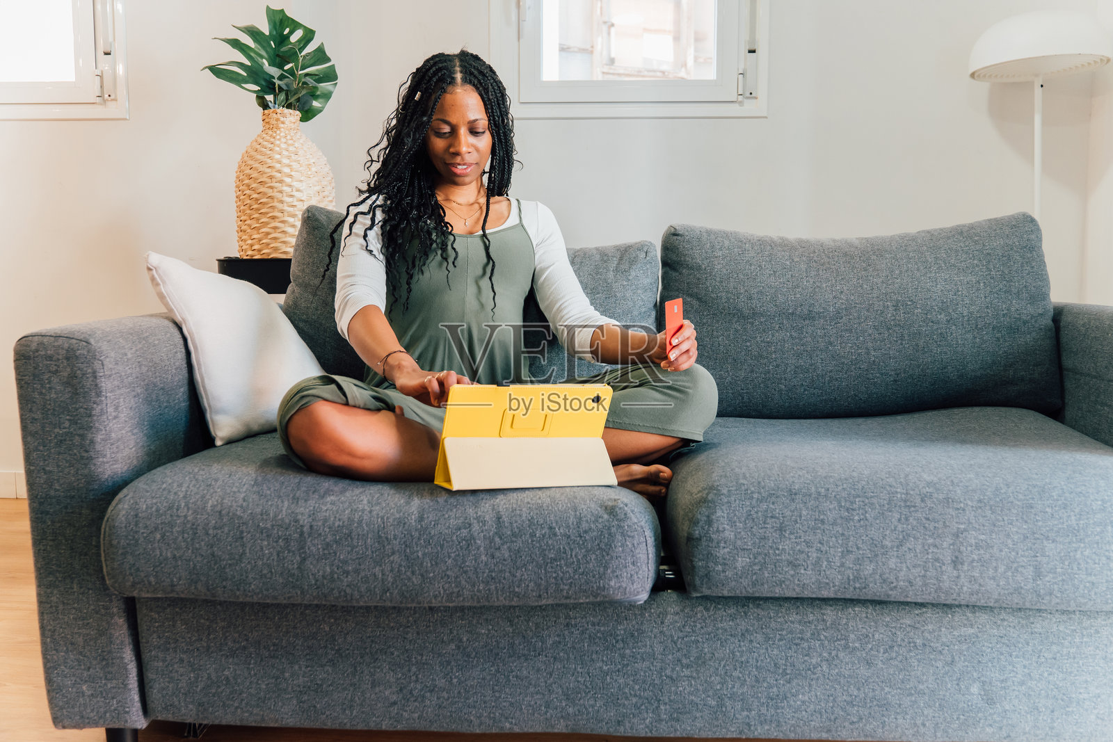 女性在客厅沙发上放松，使用平板电脑在线购物，同时手持信用卡。照片摄影图片