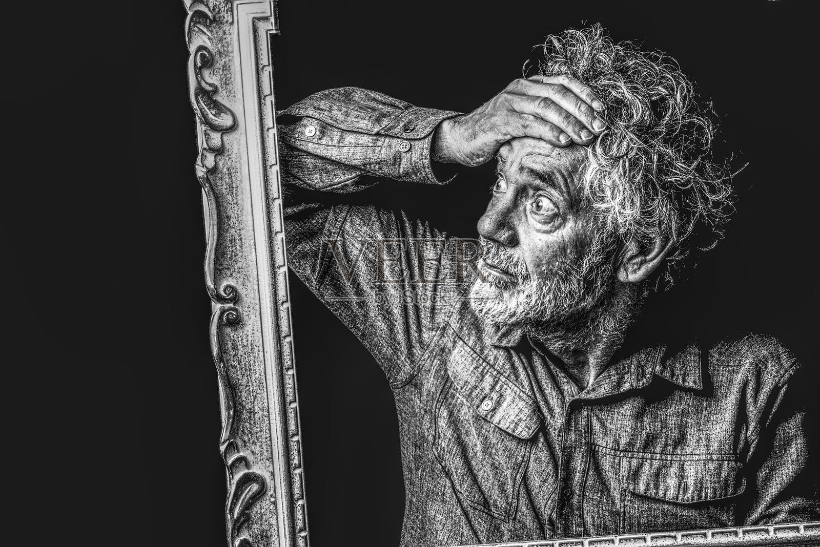 一位有着灰色头发和胡须的老年男子，透过相框凝视。照片摄影图片