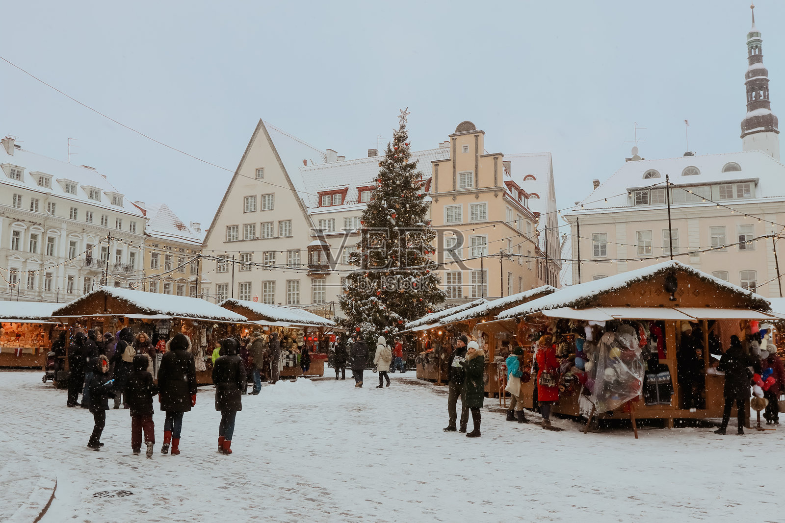 塔林，爱沙尼亚的冬季假日市场在雪天的天空下热闹非凡。照片摄影图片