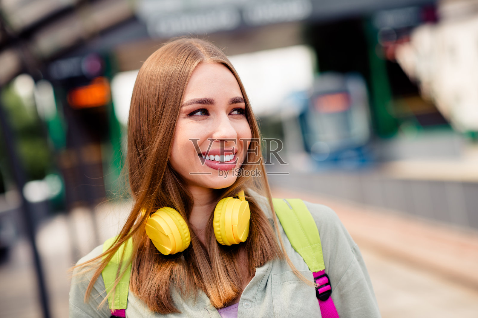 微笑的年轻女性旅行者戴着耳机，在城市的阳光明媚的户外享受美好的一天照片摄影图片