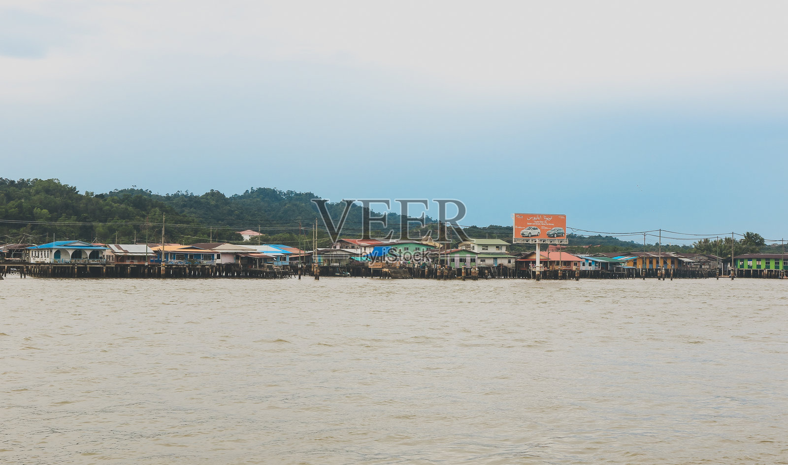 在多云的天气中，探索文莱河流沿岸的高脚屋水道照片摄影图片