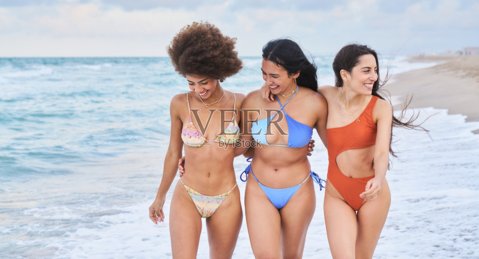 三位年轻女性在海滩上散步，享受夏季假期照片摄影图片