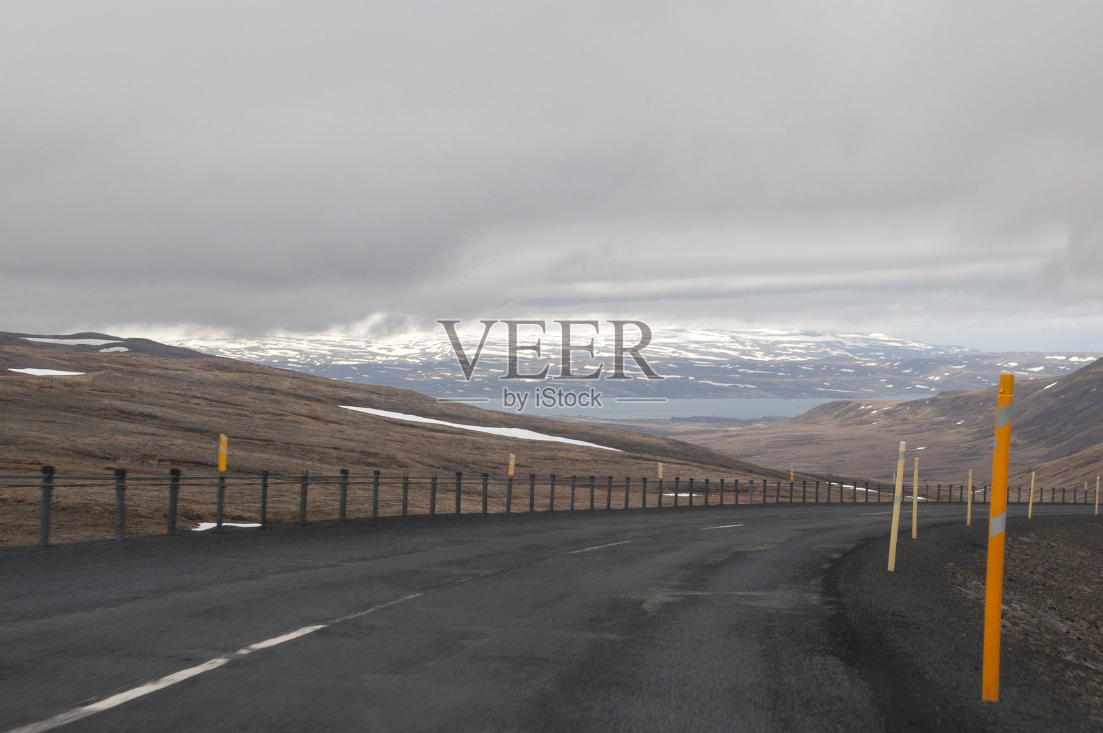 沿着山路眺望海岸，远处是白雪皑皑的山脉照片摄影图片
