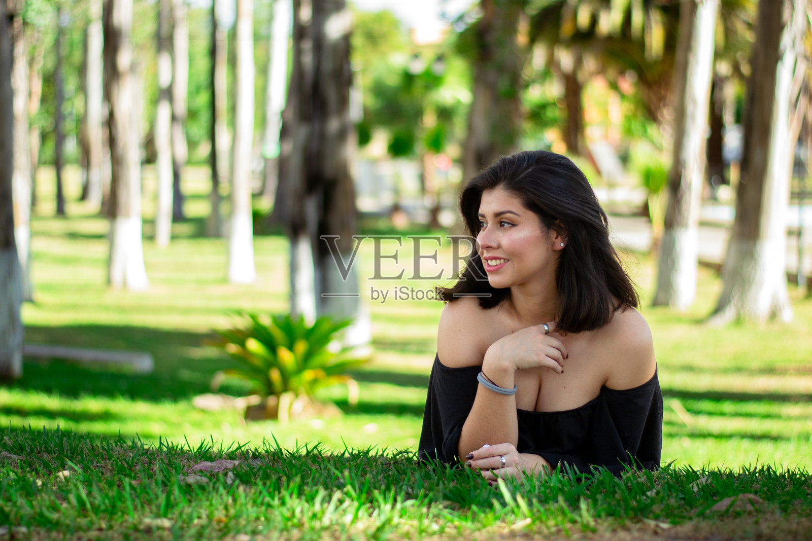 躺在草地上的西班牙裔女性侧身望去照片摄影图片