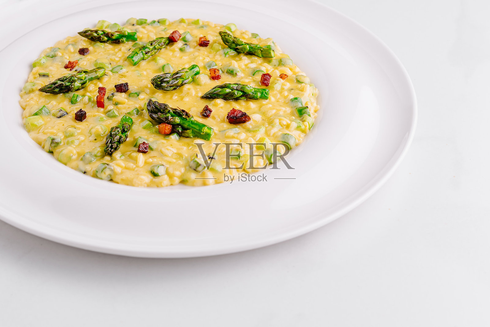 奶油蘑菇意大利调味饭配芦笋和培根，盛在白色盘子里照片摄影图片