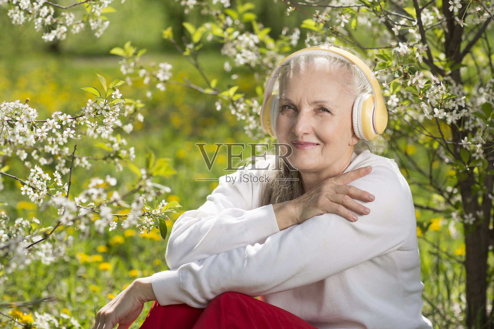 春天，带着耳机的银发老年女性在花园中放松，享受大自然的时光。音频疗愈。冥想。横幅。留白。#灰发无忧照片摄影图片