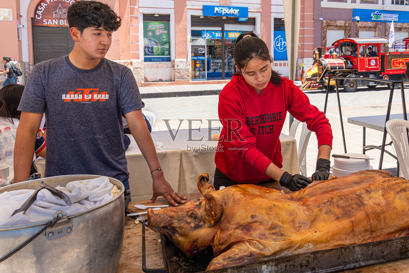 一对年轻的摊贩夫妇在厄瓜多尔提供烹饪好的大猪肉照片摄影图片