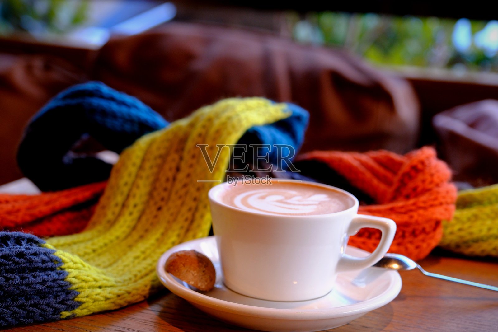 装饰着彩色围巾的咖啡拿铁杯特写。照片摄影图片