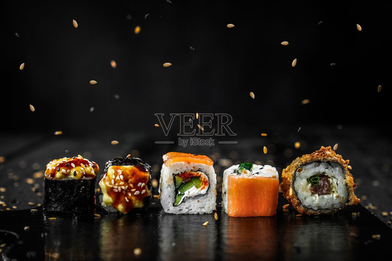 创意照片：寿司卷漂浮，海苔棒和芝麻在黑色背景上，餐厅菜单。照片摄影图片