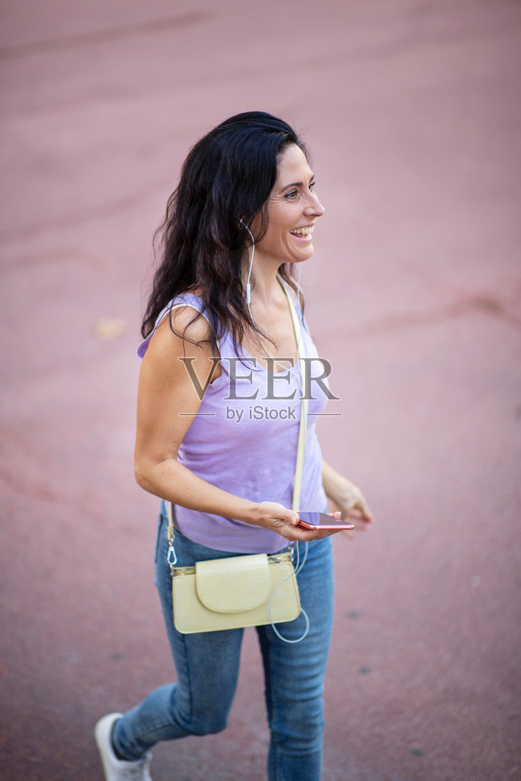 时尚女性在城市中佩戴耳机并使用手机照片摄影图片