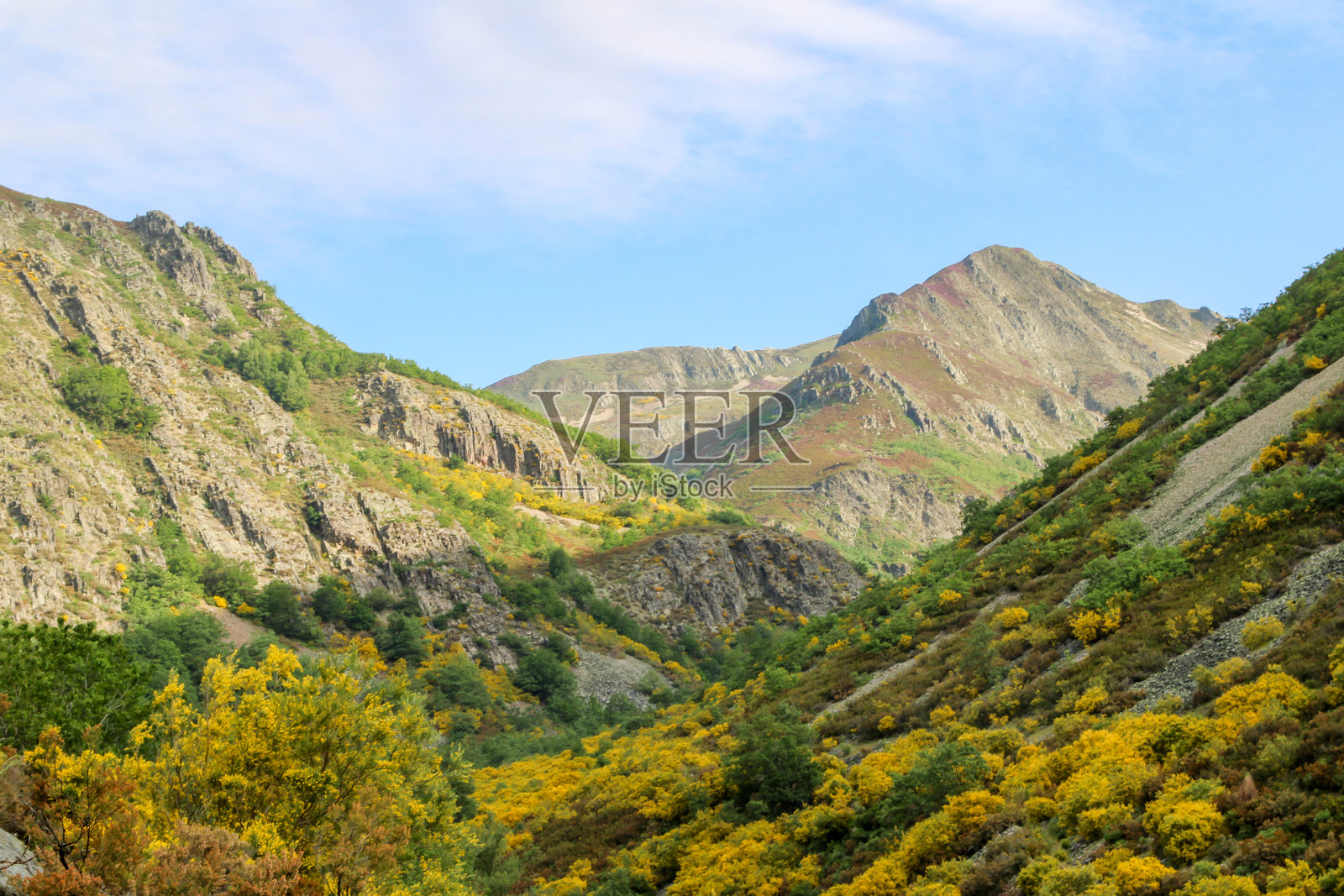 高角度俯瞰草地、山脉和天空中几朵云的风景。照片摄影图片