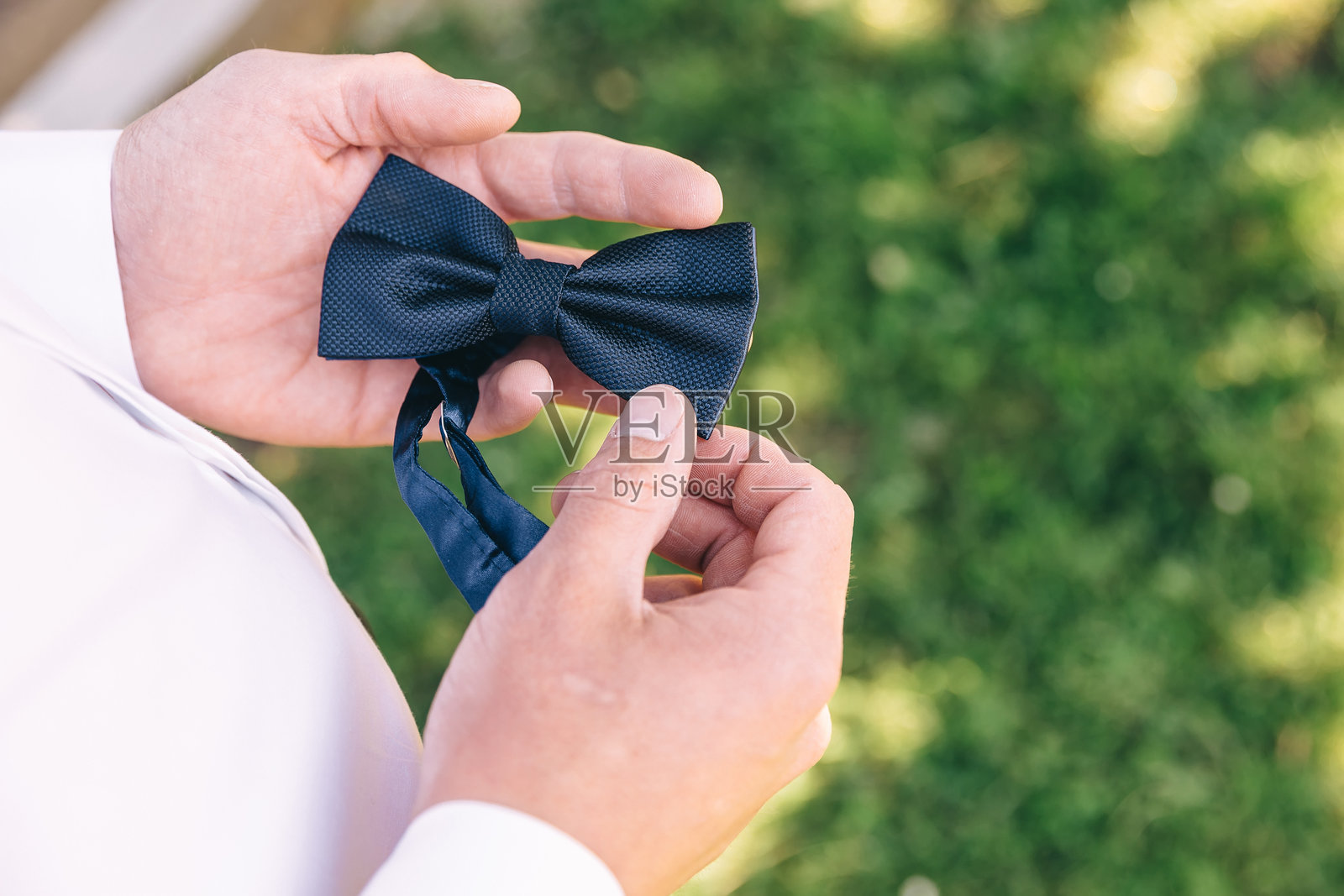 新郎的手在准备之前拿着一条黑色领结。照片摄影图片