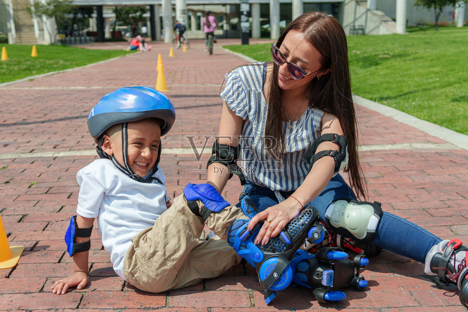 母亲微笑着帮助儿子穿上轮滑鞋照片摄影图片