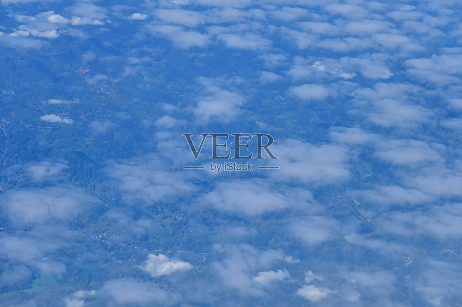 透过飞机窗户俯瞰云层下的城市景观。城市上方的云朵。从空中视角观察。照片摄影图片