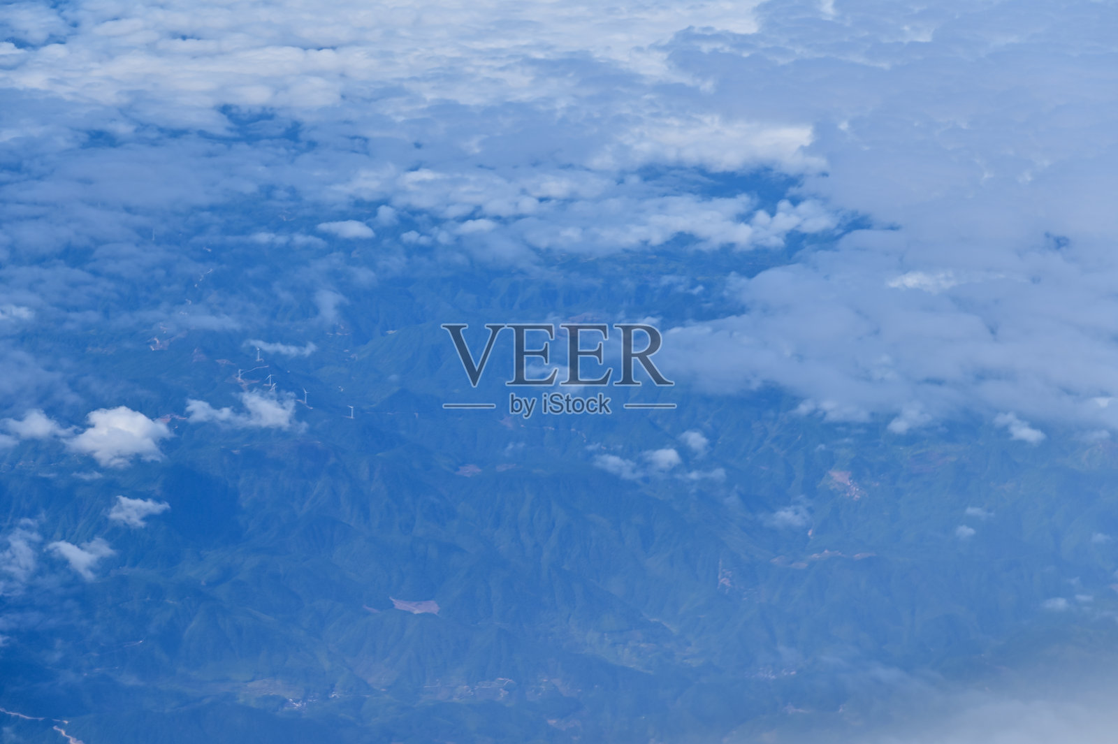 透过飞机窗户俯瞰云层下的城市景观。云层在城市上方。从空中视角观察。照片摄影图片