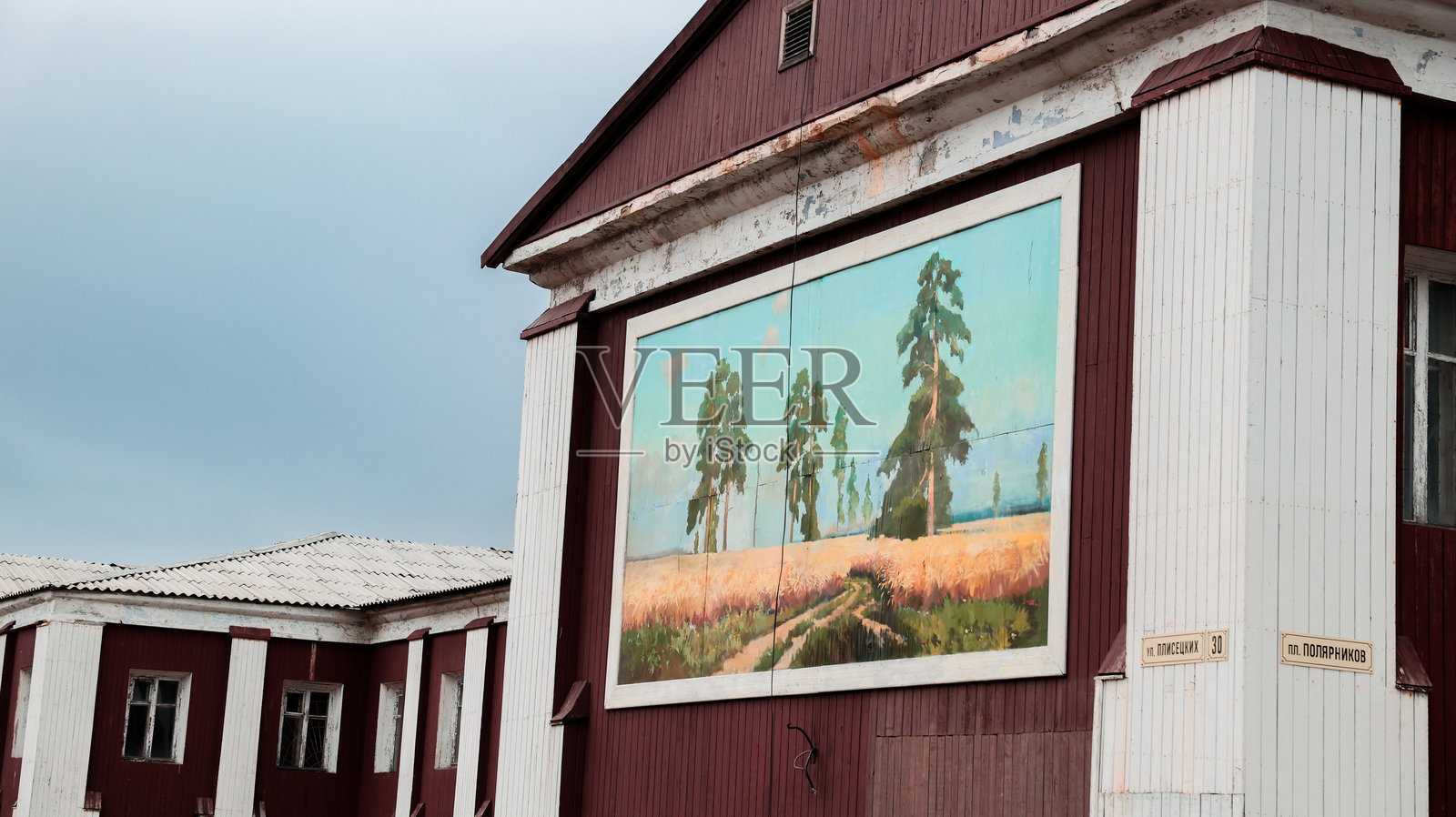 白昼时分，巴伦支堡建筑上的色彩斑斓的壁画描绘了树木。照片摄影图片