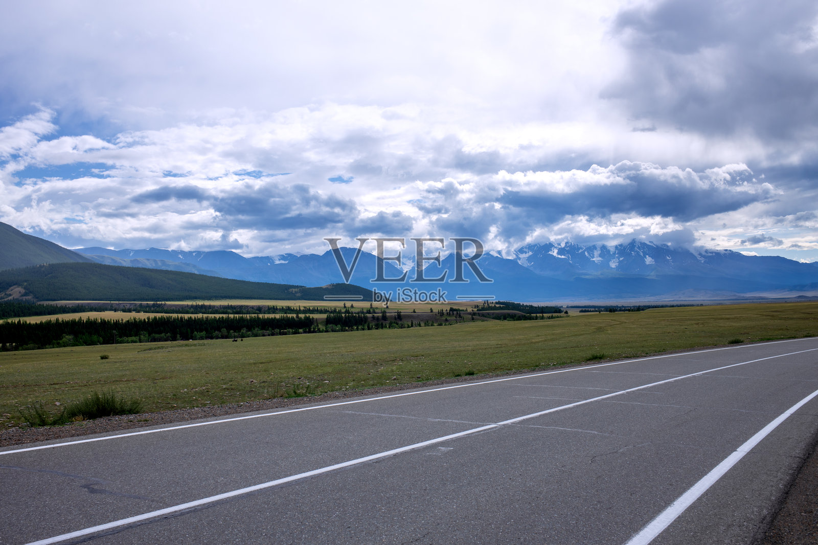 一条有白色分隔线的沥青公路，背景是山峰和美丽的天空。旅行中的横向照片。照片摄影图片