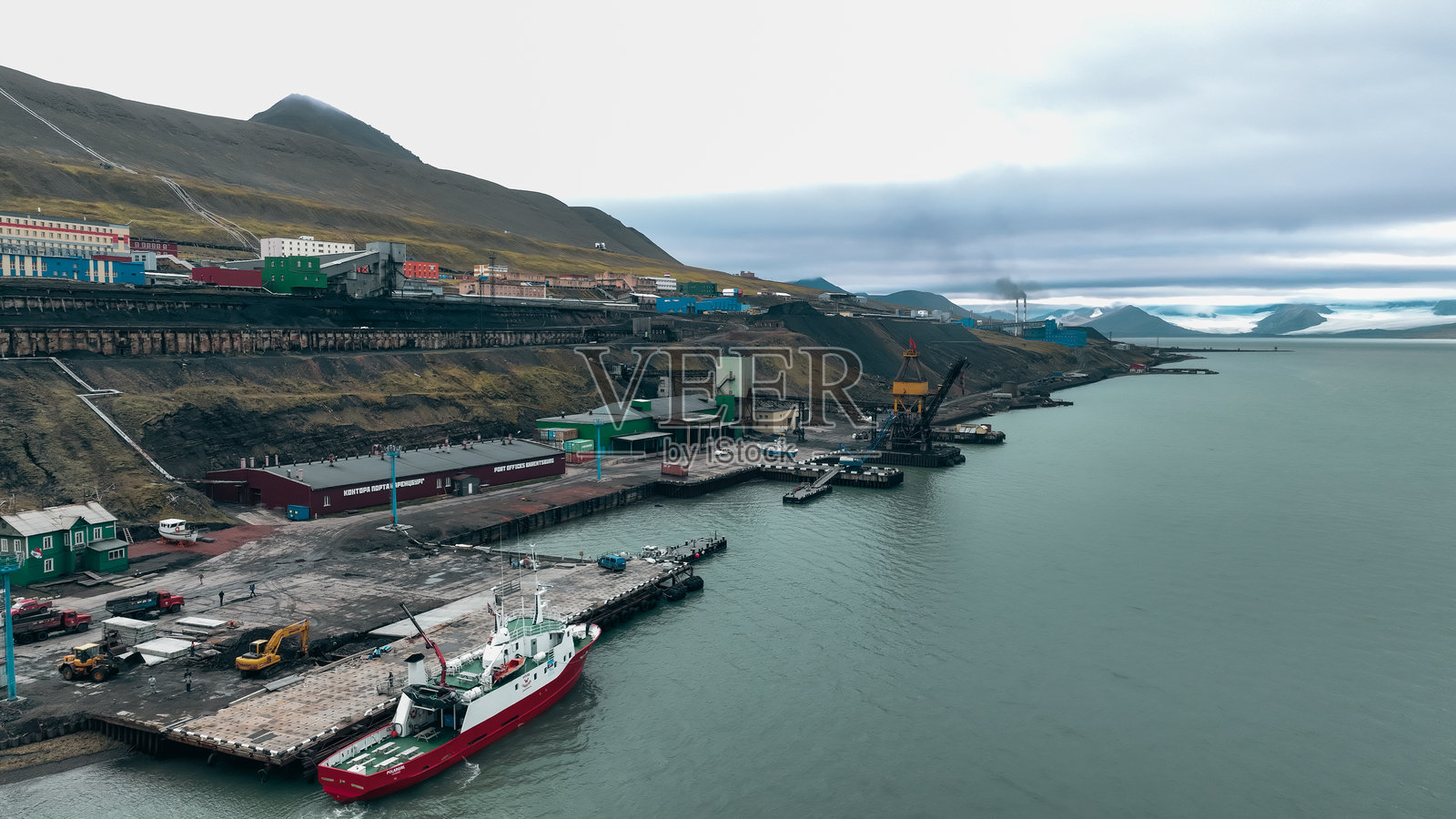 巴伦茨堡港口的航运活动与阴云密布的山脉照片摄影图片