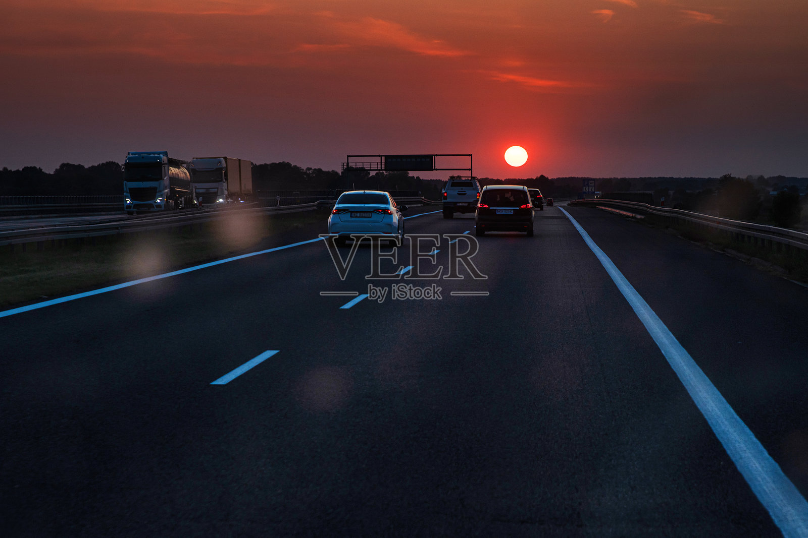 日落时分的风景公路，汽车和卡车穿过脏污的挡风玻璃。旅行、交通、自由以及开阔道路上傍晚天空之美的概念。留白空间。照片摄影图片