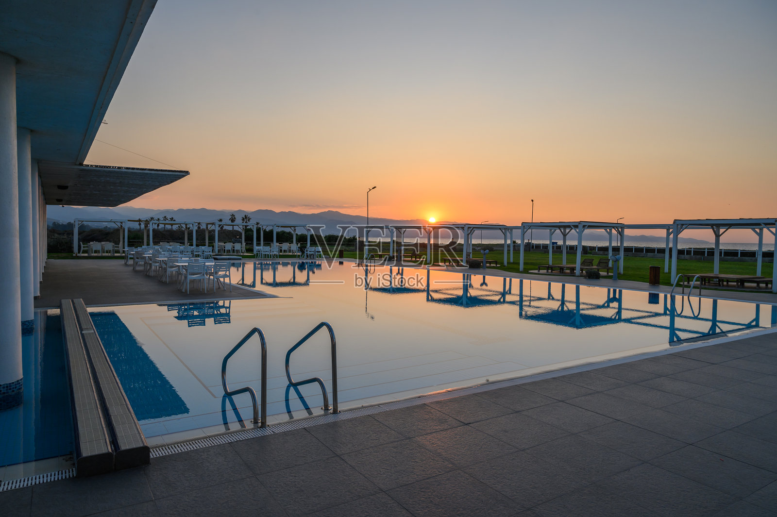 宁静的海岸游泳池上空的夕阳倒影照片摄影图片