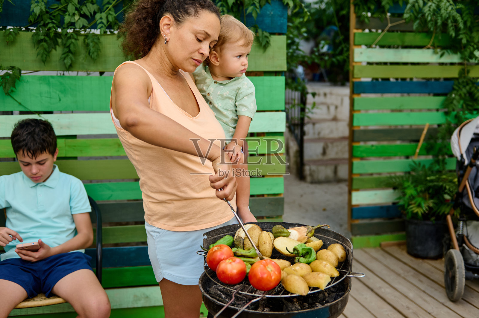母亲在阳光明媚的日子里与家人一起户外烧烤蔬菜照片摄影图片