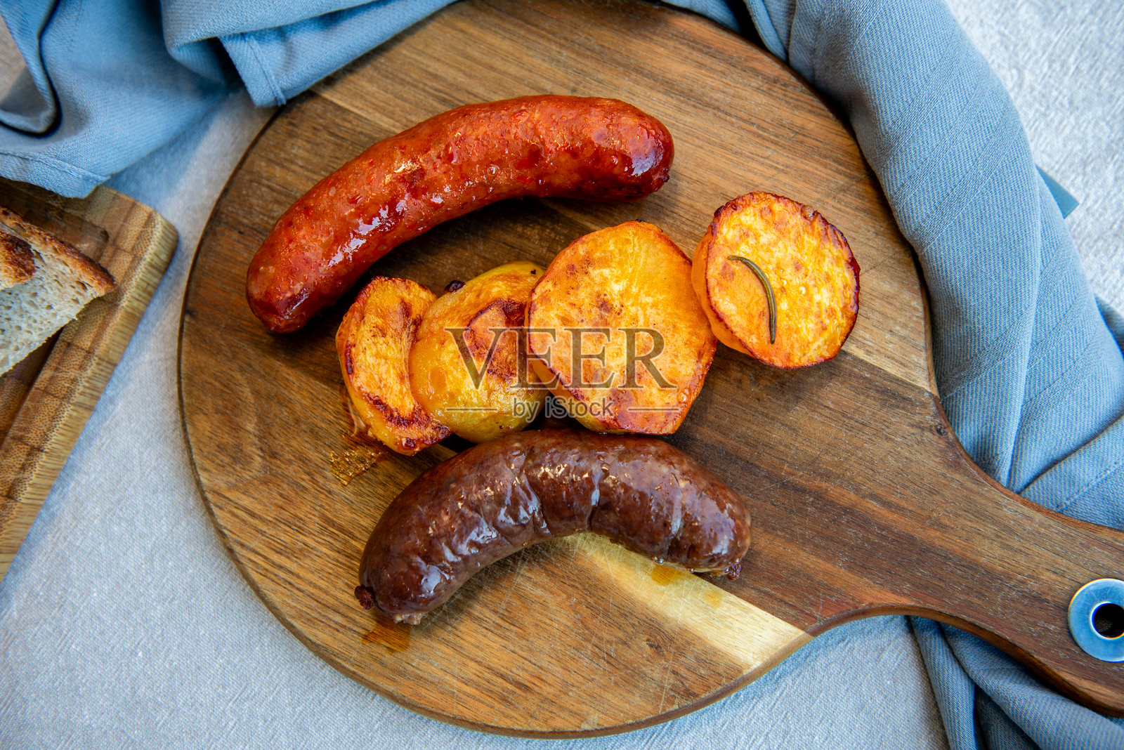 自制香肠特写，放在木砧板上，旁边有土豆。传统自制美食照片摄影图片