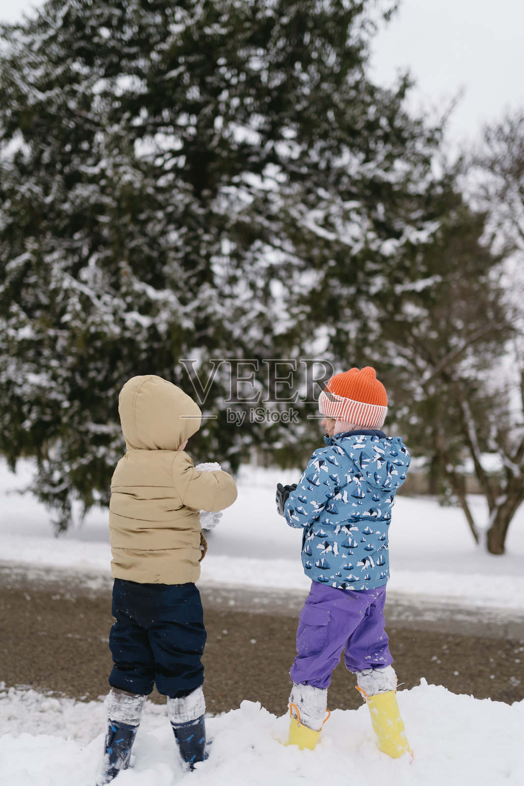裹得严严实实的孩子们在冬天的雪地里玩耍照片摄影图片