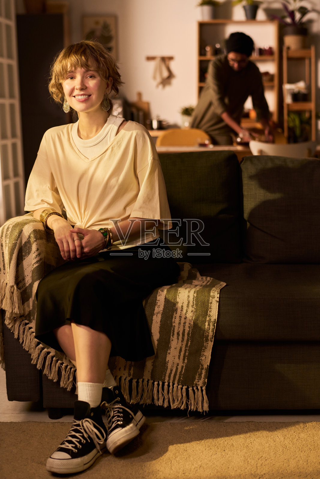 微笑的女性坐在沙发上，与朋友一起做饭照片摄影图片