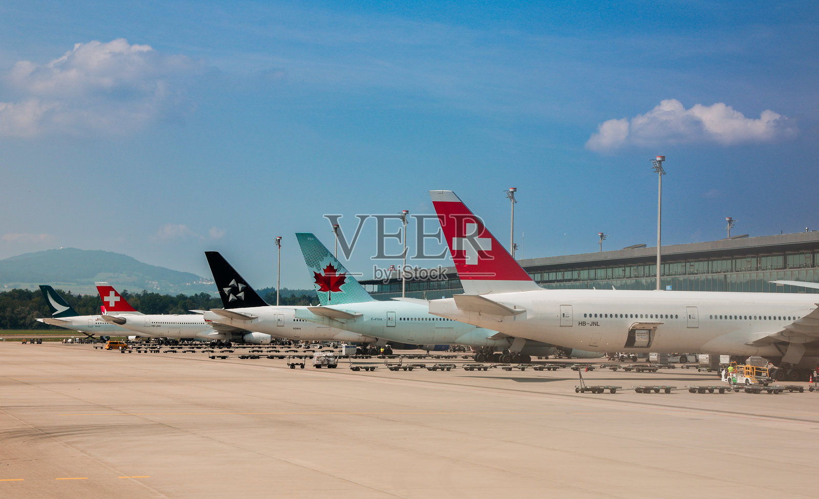 在瑞士的一个阳光明媚的日子里，苏黎世机场停放着飞机，天空晴朗。照片摄影图片