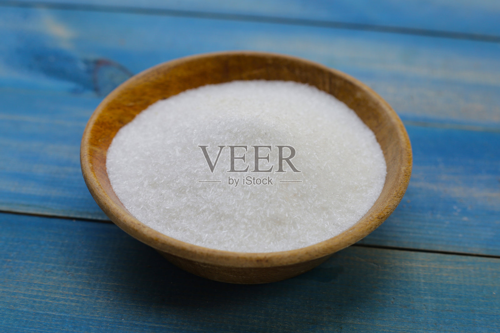 木质背景上的碗中盛有味精。照片摄影图片