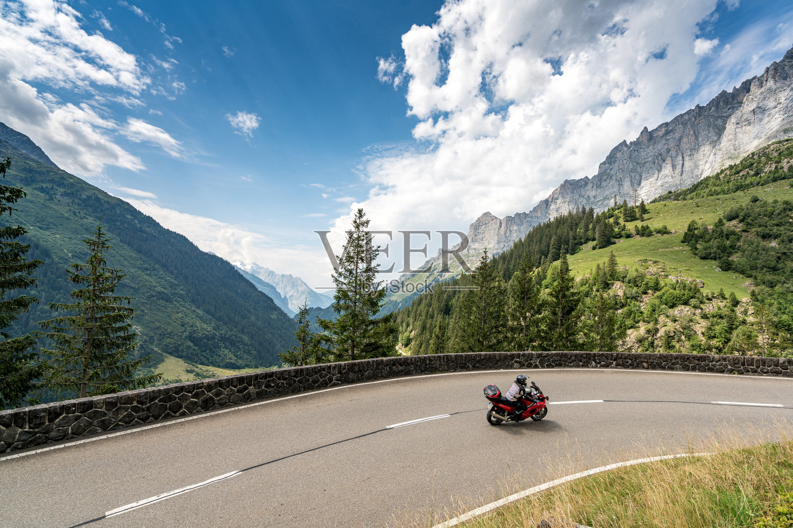 一辆摩托车在瑞士阿尔卑斯山的蜿蜒道路上行驶。照片摄影图片
