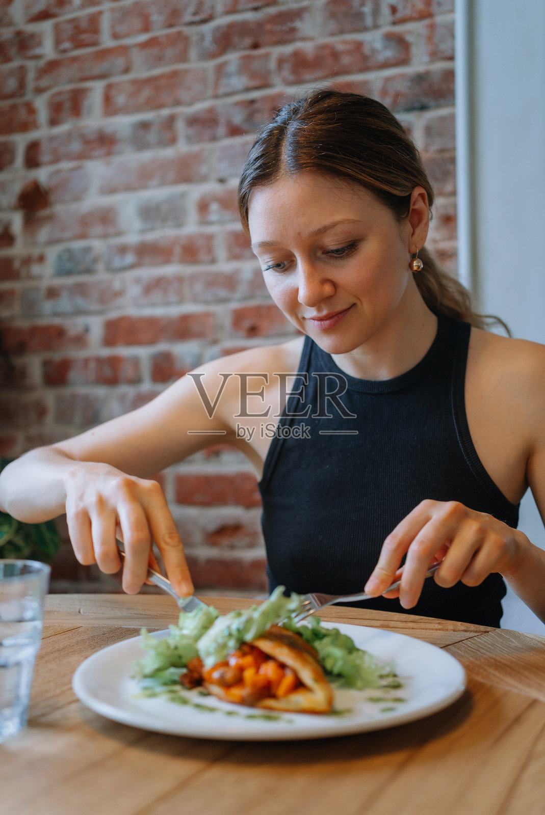 年轻女性在舒适的咖啡馆环境中享用健康餐。照片摄影图片