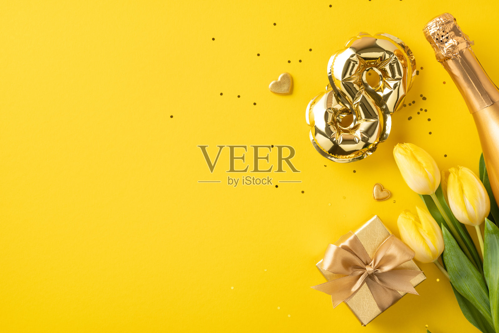 节日布置，包含黄色郁金香、一个包裹的礼物和金色装饰，背景为黄色，营造出庆祝和愉快的氛围照片摄影图片
