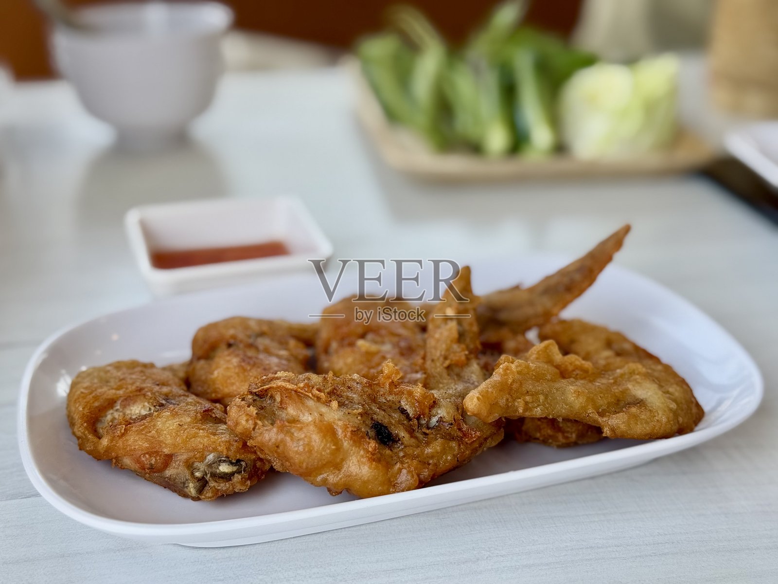 白盘上的炸鸡配酱汁和黄瓜。照片摄影图片