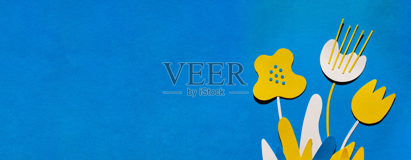 蓝色背景上有白色和黄色的手工纸花，伴有阴影。春季或夏季的极简背景。照片摄影图片