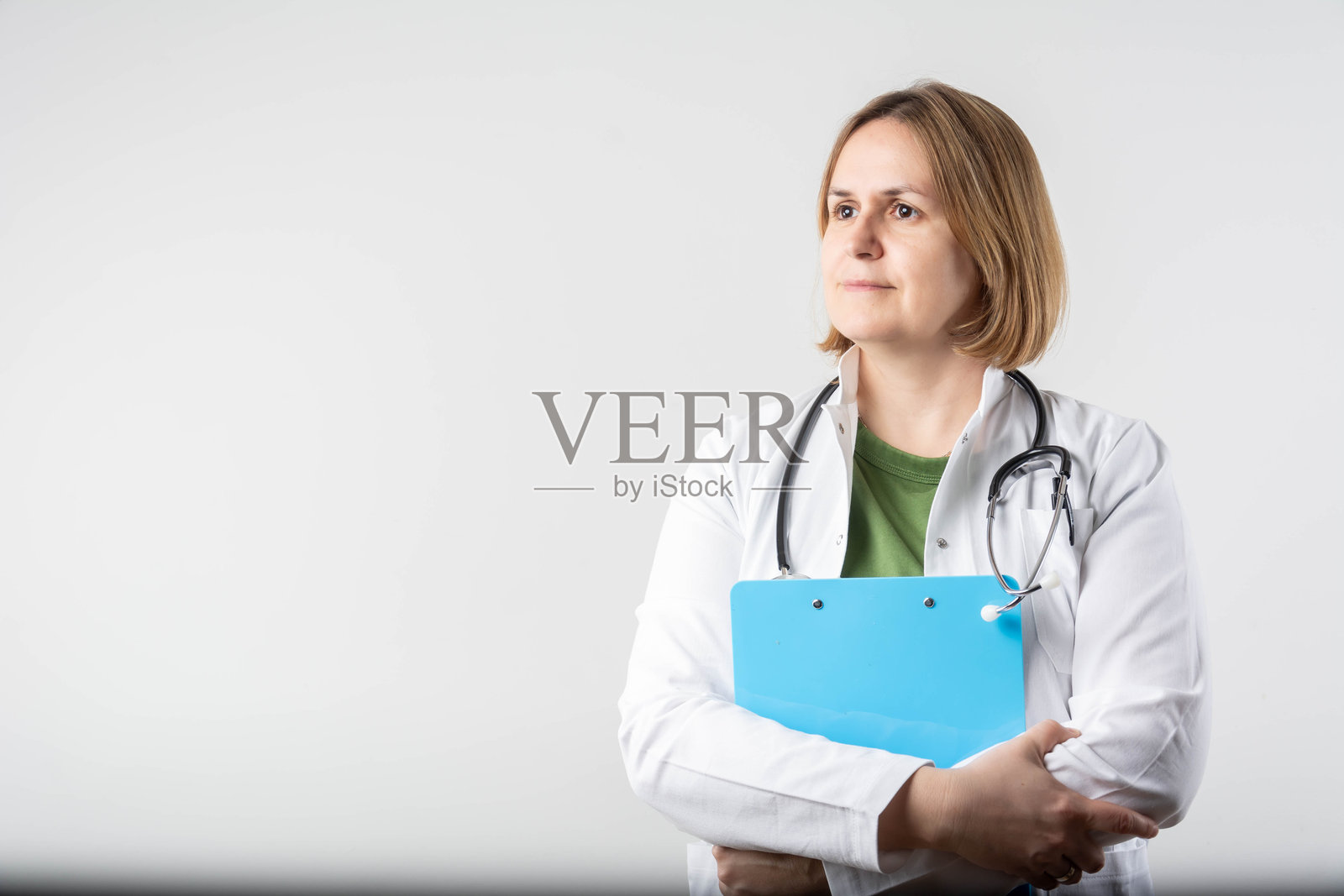 微笑着手持夹板的美丽女医生照片摄影图片