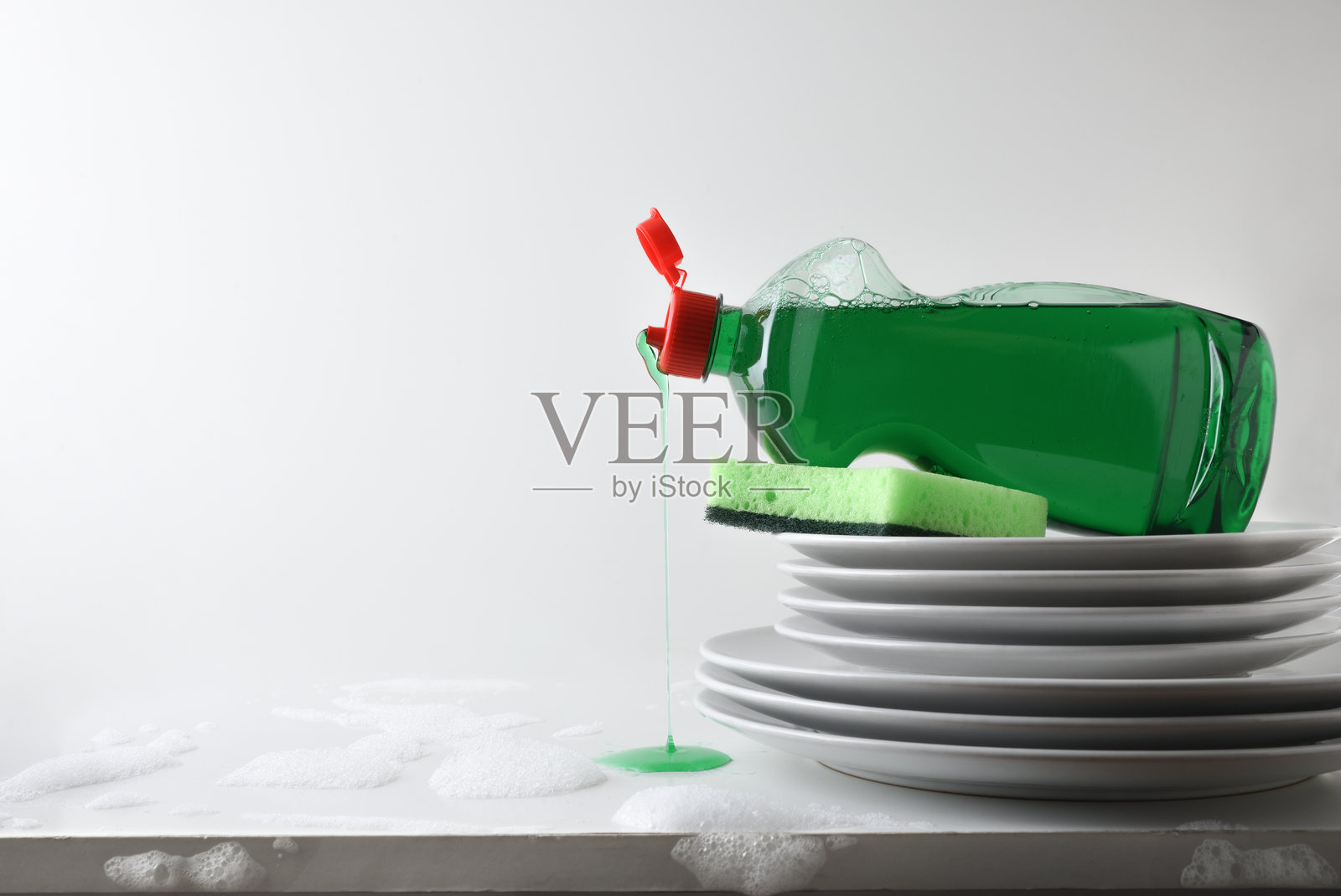 一堆盘子和洗碗机清洁剂瓶子掉落在台面上照片摄影图片