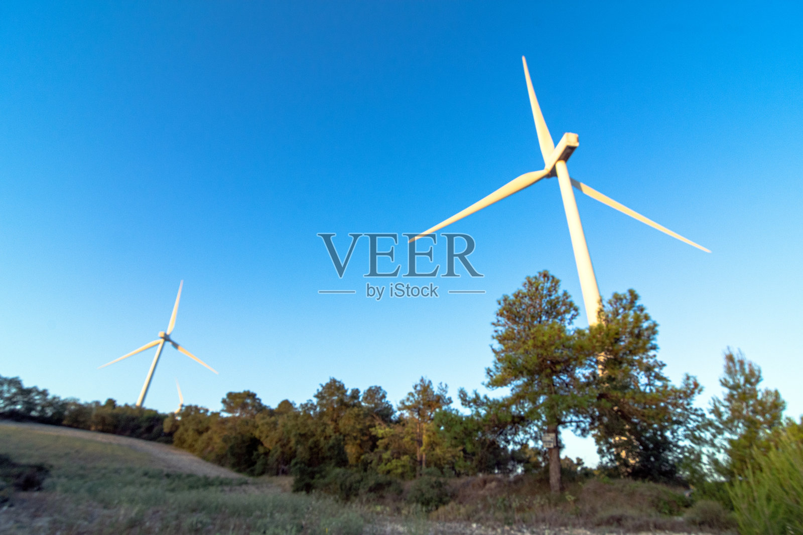 加泰罗尼亚乡村风景中的风力涡轮机，周围有森林和田野照片摄影图片