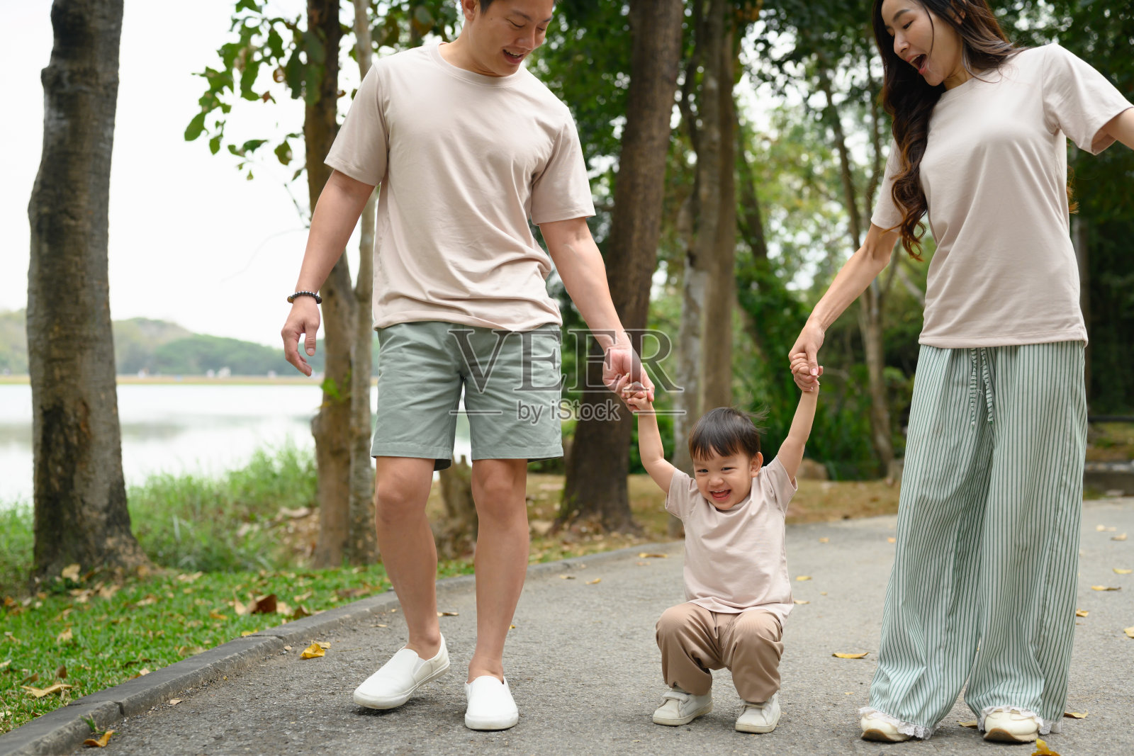 父母牵着幼儿的手在公园小径上散步照片摄影图片