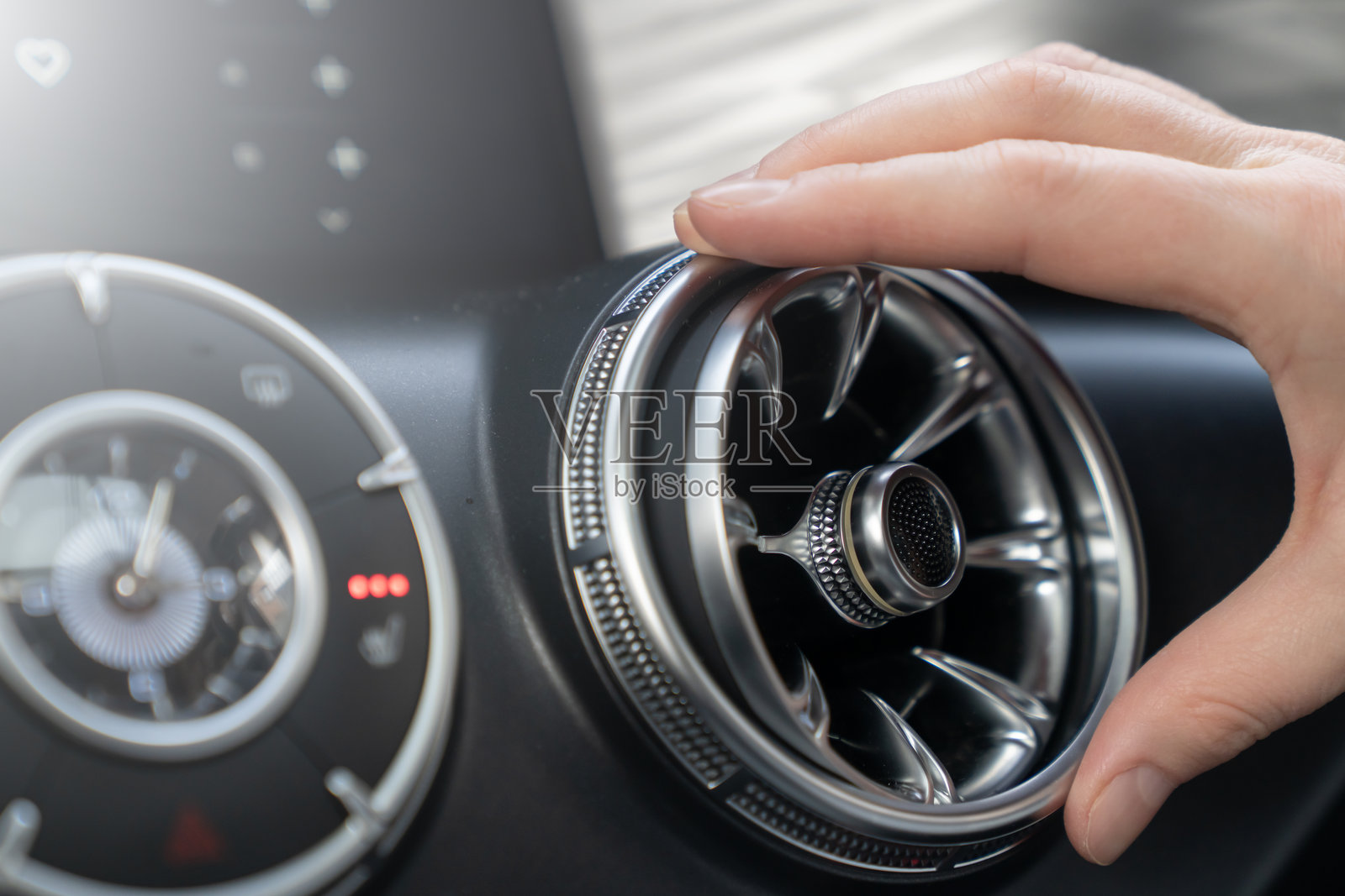 一只手轻柔地调整着时尚的汽车空调出风口，以确保最佳舒适度和有效的气候控制。调整汽车空调出风口以实现最佳舒适和效率。照片摄影图片