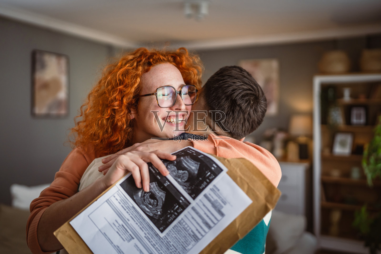 拥抱的情侣手持超声波孕妇的宝宝照片照片摄影图片