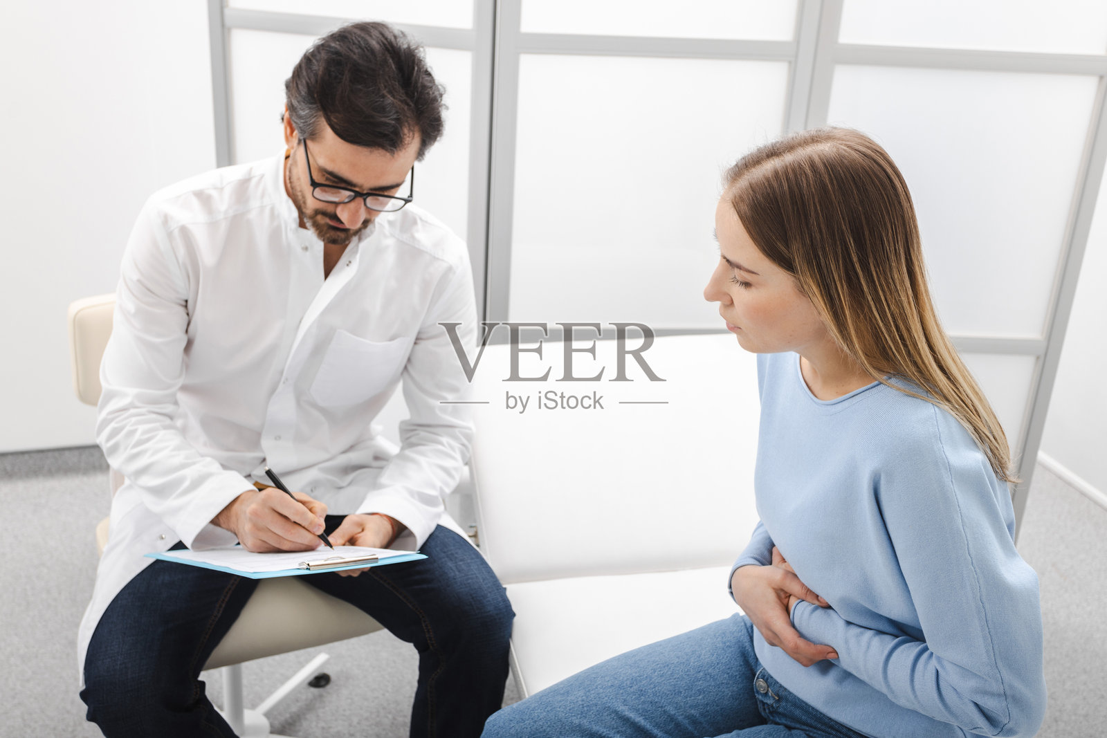 医生为一位腹痛女性患者开处方治疗。胃肠病学照片摄影图片