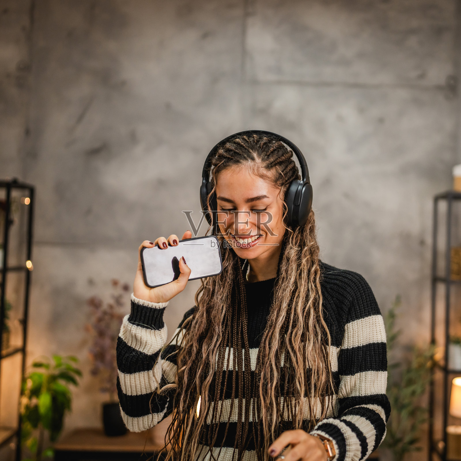 快乐的年轻女性在家中戴着耳机听音乐并唱歌照片摄影图片